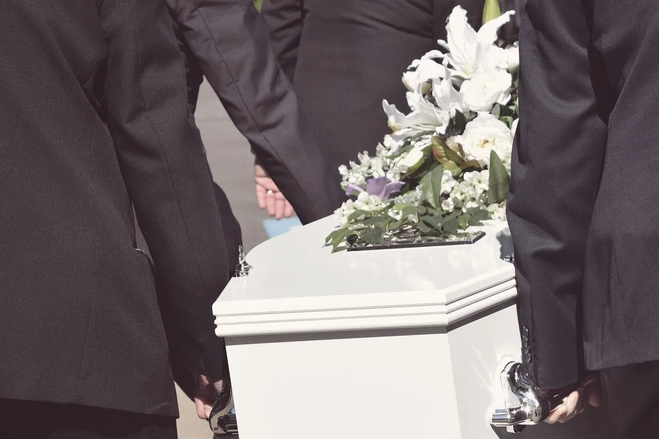 Pallbearers carrying a casket topped with lilies