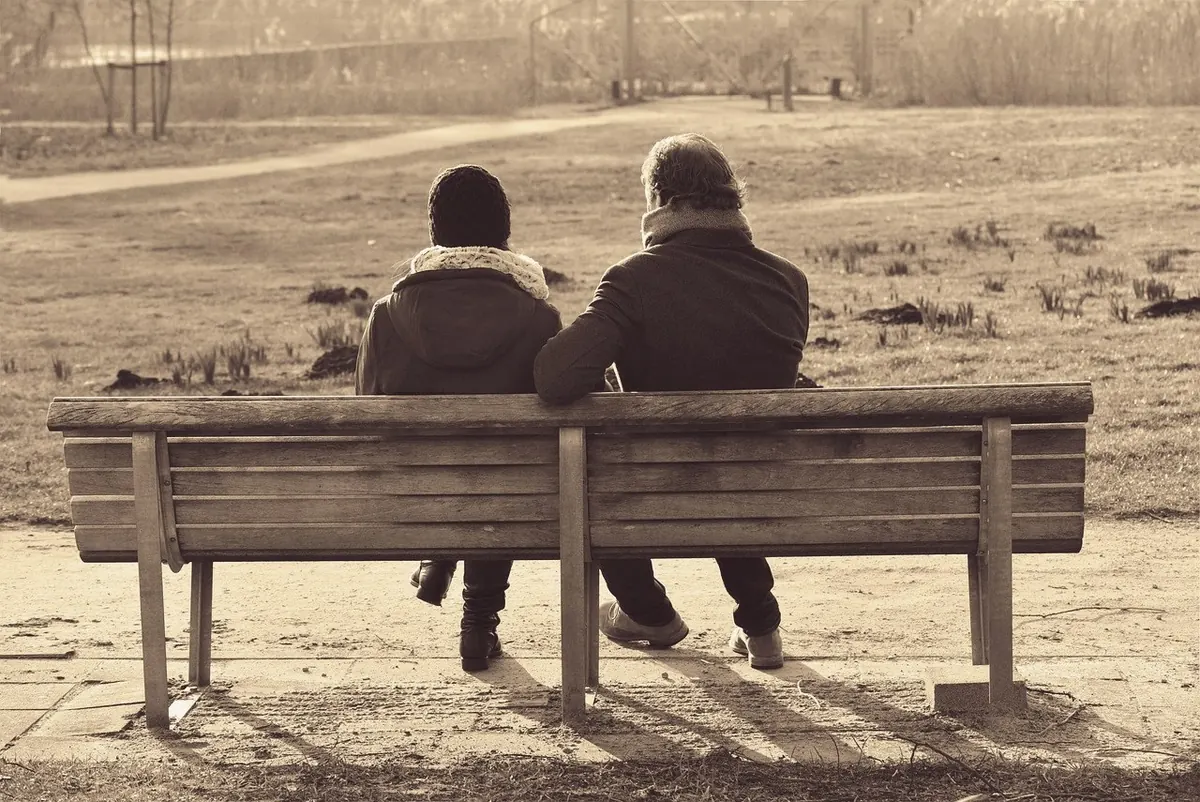 An older couple sitting together on a park bench