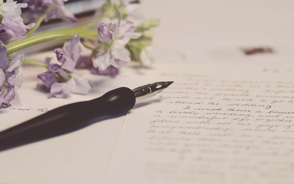 A pen and handwritten note beside fresh flowers