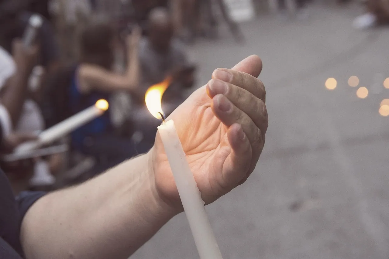 Hands holding lit candles at a vigil