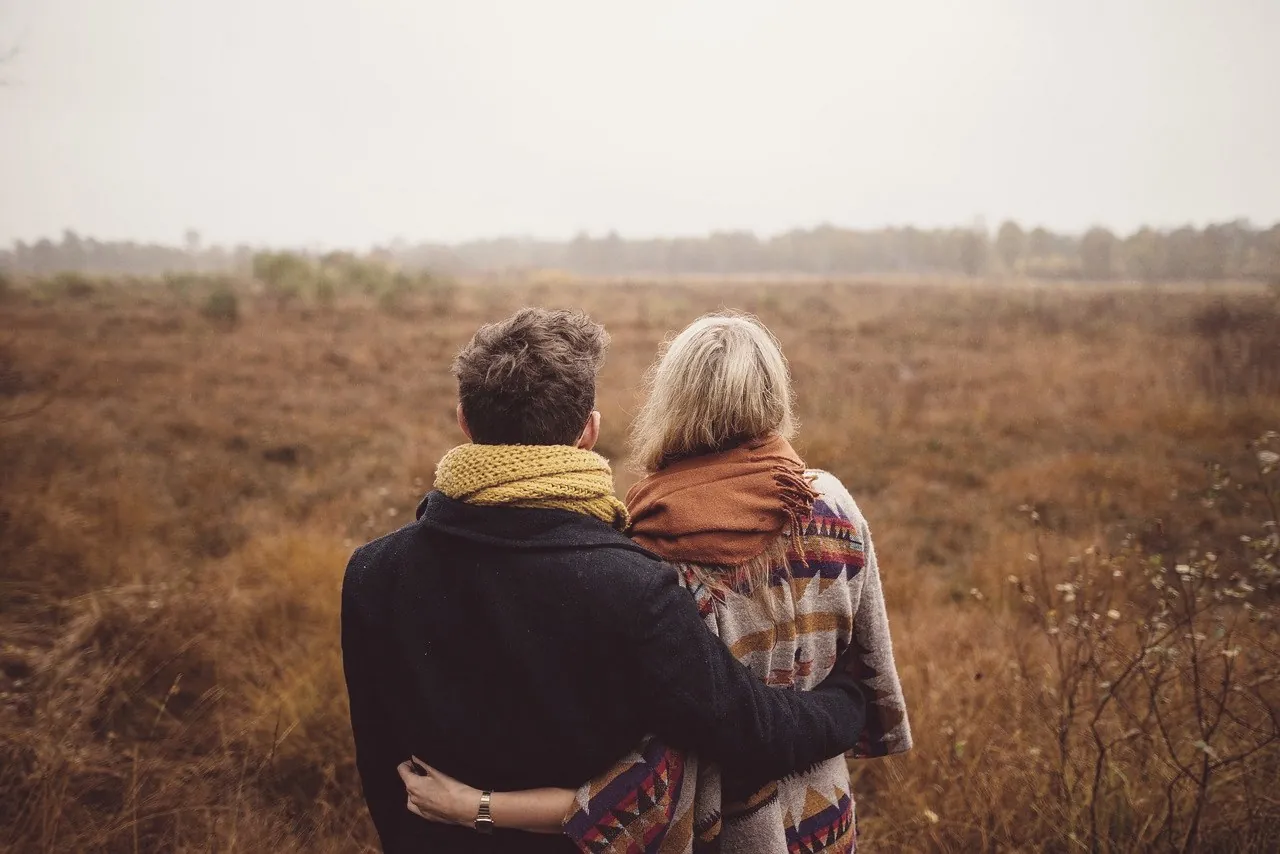 A couple wrapped together outdoors in autumn